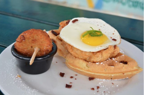 a plate with chicken topped on waffles with a fried egg on top of the chicken 